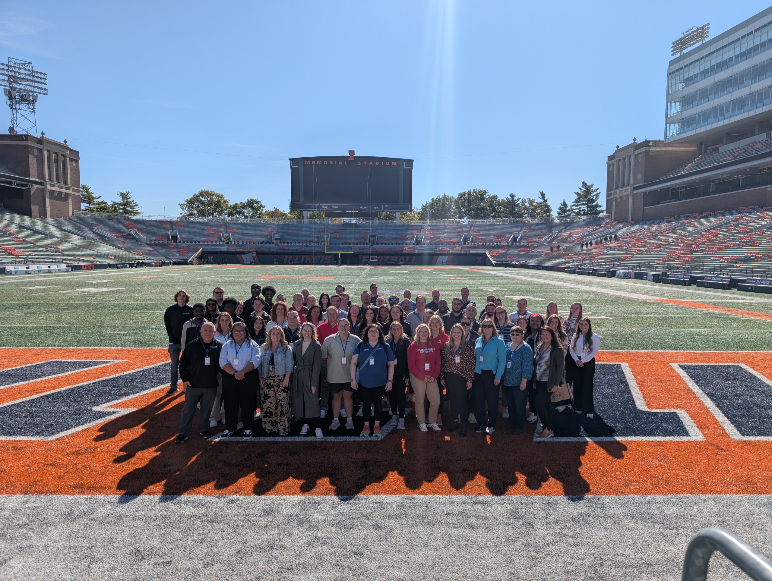 A large group of people standing on a football field outside.